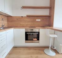 Eine Küche in einem Studio-Apartment mit weißen Schränken und einem Boden in Holzoptik.