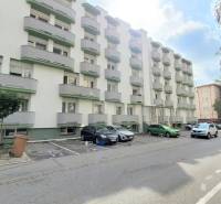 Parkplatz und Wohnhäuser in der Ondavská Straße in Bratislava - Ružinov, umgeben von Grünflächen.