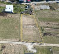 Baugrundstücke in Papradno, umgeben von Grünflächen und mit befestigter Straße.