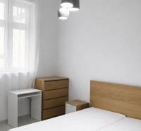 Schlafzimmer mit Holzmöbeln und Hängelampen in einer Zweizimmerwohnung.