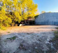 Gewerbegrundstücke in Nitra mit Blechhalle und Umzäunung in bewaldeter Umgebung.