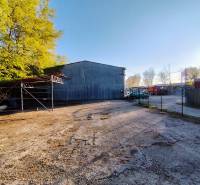 Industrieobjekt mit Parkplatz, umgeben von Bäumen in Nitra, geeignet für kommerzielle Nutzung.