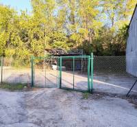Ein Zaun mit einem Metallbauwerk, umgeben von Bäumen, im Gewerbegebiet von Nitra.