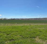 Landwirtschaftliche und forstwirtschaftliche Flächen in Dežerice mit weitläufigen Wiesen und klarem Himmel.