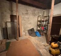 Úložný priestor v rodinnom dome s policami a náhodne uloženými predmetmi.