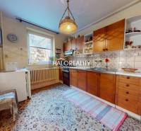 Küche in einem Einfamilienhaus mit Holzschränken, Teppichboden und einer Hängelampe.
