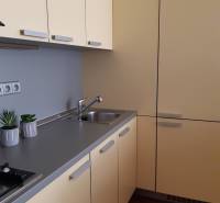 Küche in einer 3-Zimmer-Wohnung mit cremefarbenen Schränken und einem Boden in Holzoptik.