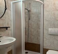 Badezimmer mit Toilette, Duschkabine und Waschbecken in einem Einfamilienhaus, gefliest.