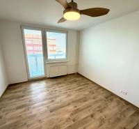 Ein Zimmer in einem Studio-Apartment mit einem Boden in Holzoptik, einem Deckenventilator und einem Fenster mit Aussicht.