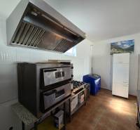 Gastronomiebereiche mit Ofen, Dunstabzugshaube und Kühlschrank, Boden mit Holzdekor.