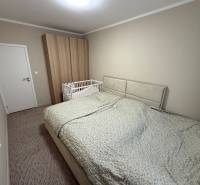 Schlafzimmer mit grauem Bett, Kinderbett und Kleiderschrank in einer 4-Zimmer-Wohnung.
