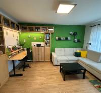 Wohnzimmer mit Sofa, Schreibtisch und Holzboden in einer Vierzimmerwohnung.