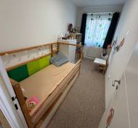 Kinderzimmer in einer 4-Zimmer-Wohnung mit Bett, Kommode und bunten Vorhängen.