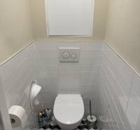 Toilette in einer 4-Zimmer-Wohnung mit geometrischen Fliesen und weißen Kacheln.