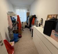 Ein Zimmer mit Schränken und Kleidung in einer 4-Zimmer-Wohnung, dominiert von weißen Wänden und Teppichboden.