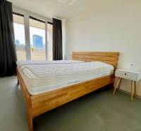 Schlafzimmer mit einem Holzbett, einem Nachttisch und einem Balkon in einer 3-Zimmer-Wohnung.