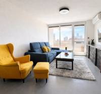 Wohnzimmer in einer 3-Zimmer-Wohnung mit gelbem Sessel, blauem Sofa und Fernseher an der Wand.