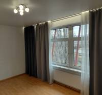 Ein Zimmer mit einem großen Fenster, Verdunkelungsvorhängen und einem Boden mit Holzdekor. Geschäftsräume.