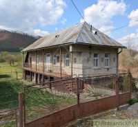 Ein Einfamilienhaus in Zubné mit einem Blechdach, einem Zaun und einer ländlichen Umgebung.