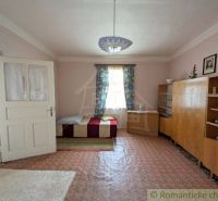 Ein Zimmer mit einfacher Einrichtung, einem Bett und Teppichen in einem Einfamilienhaus.