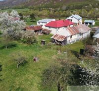 Ein Einfamilienhaus in Zubné mit Garten, Bäumen und älteren Wirtschaftsgebäuden.