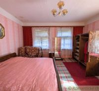 Schlafzimmer im Einfamilienhaus mit Bett, Kleiderschrank und rot-rosa Tapete.