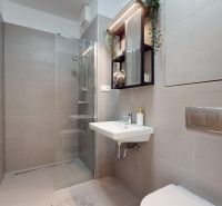 Badezimmer mit Toilette, Duschkabine und Spiegel in einer Einzimmerwohnung.