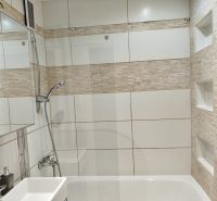 Badezimmer mit Badewanne und Fliesen in einer Einzimmerwohnung.