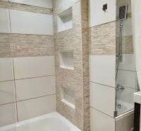 Badezimmer in einer Einzimmerwohnung mit Badewanne und Fliesen in Beigetönen.