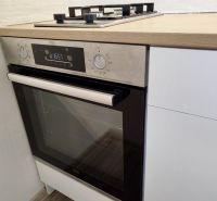Küche mit Kombibackofen und Kochfeld in einer Einzimmerwohnung, Boden mit Holzdekor.