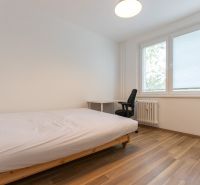 Schlafzimmer mit einem Einzelbett, einem Schreibtisch und einem Boden mit Holzdekor in einer 3-Zimmer-Wohnung.