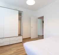Schlafzimmer in einer 3-Zimmer-Wohnung mit weißem Schrank und Boden in Holzoptik.