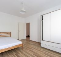 Schlafzimmer mit einem Holzbett, einem weißen Schrank und einem Boden mit Holzdekor in einer 3-Zimmer-Wohnung.