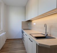 Küche in einer 3-Zimmer-Wohnung mit Holzboden und hellen Schränken.