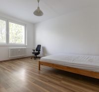 Helles Schlafzimmer mit Bett und Arbeitsstuhl, Boden mit Holzdekor.