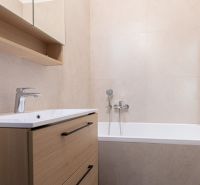 Badezimmer in einer 3-Zimmer-Wohnung mit Badewanne und Schrank mit Holzdekor.