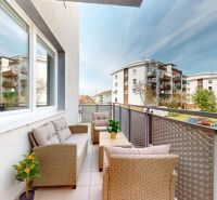 Ein Balkon mit Rattanmöbeln und Blick auf Wohnhäuser in der Koceľova-Straße in Slovenský Grob.