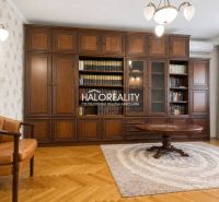 Wohnzimmer in einer 3-Zimmer-Wohnung mit Bibliothek, Sessel und Holzboden.