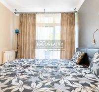 Schlafzimmer in einer 3-Zimmer-Wohnung mit Blumenmuster auf der Bettwäsche und Vorhängen.
