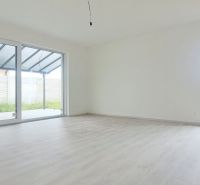 Ein geräumiges Zimmer mit großen Fenstern und einem Holzboden in einem Einfamilienhaus.