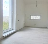 Innenraum eines Einfamilienhauses mit Holzboden und großem Fenster.