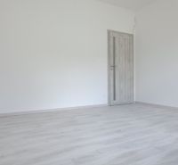 Ein leerer Raum mit Holzboden und geschlossener Tür in einem Einfamilienhaus.