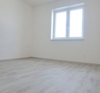 Ein Zimmer mit einem Fenster und einem Boden in Holzoptik in einem Einfamilienhaus.
