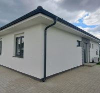 Ein Einfamilienhaus in Topoľnica mit weißer Fassade und gepflasterter Terrasse.