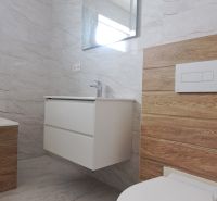 Badezimmer in einem Einfamilienhaus mit Waschbecken, Spiegel und Boden mit Holzdekor.