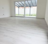 Innenraum eines Einfamilienhauses mit großem Fenster und Boden in Holzoptik.