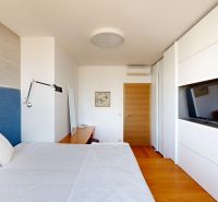 Schlafzimmer in einer 4-Zimmer-Wohnung mit Bett, Holzboden und Wandfernseher.