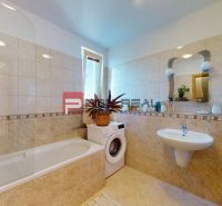 Badezimmer in einer 2-Zimmer-Wohnung mit Badewanne, Waschmaschine, Waschbecken und Spiegel.