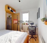 Schlafzimmer in einer 2-Zimmer-Wohnung mit Bett, Schreibtisch und Boden mit Holzdekor.