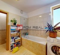 Badezimmer in einer 2-Zimmer-Wohnung mit Badewanne, Waschmaschine und Regal zur Aufbewahrung von Zubehör.